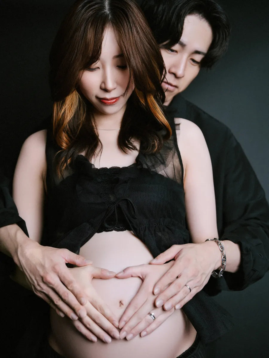 黒い衣装でお腹を囲みハートをつくる夫婦のマタニティフォト｜仙台フォトスタジオQnNe（キュンネ）