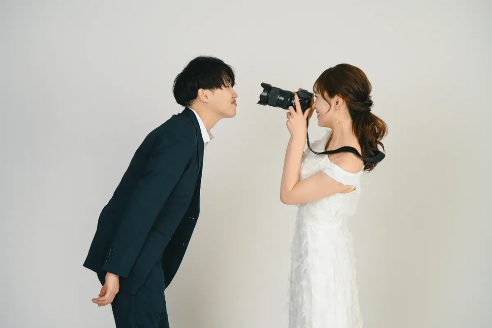 カメラを構える新婦と笑顔で近づく新郎の自然なやりとり｜仙台フォトスタジオQnNe