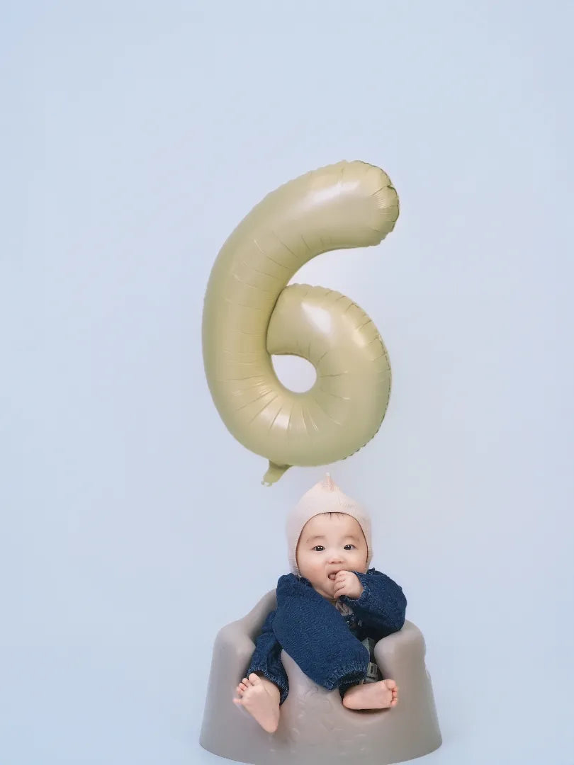 数字の6の風船と一緒に笑顔を見せる赤ちゃんのハーフバースデーフォト。仙台フォトスタジオQnNe(キュンネ)
