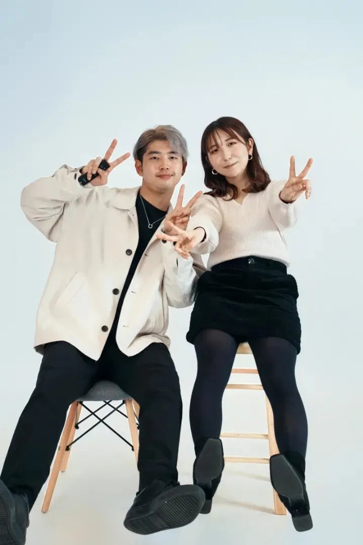 白背景で椅子に座った男女がピースサインをするカジュアルフォト。仙台フォトスタジオQnNe(キュンネ)