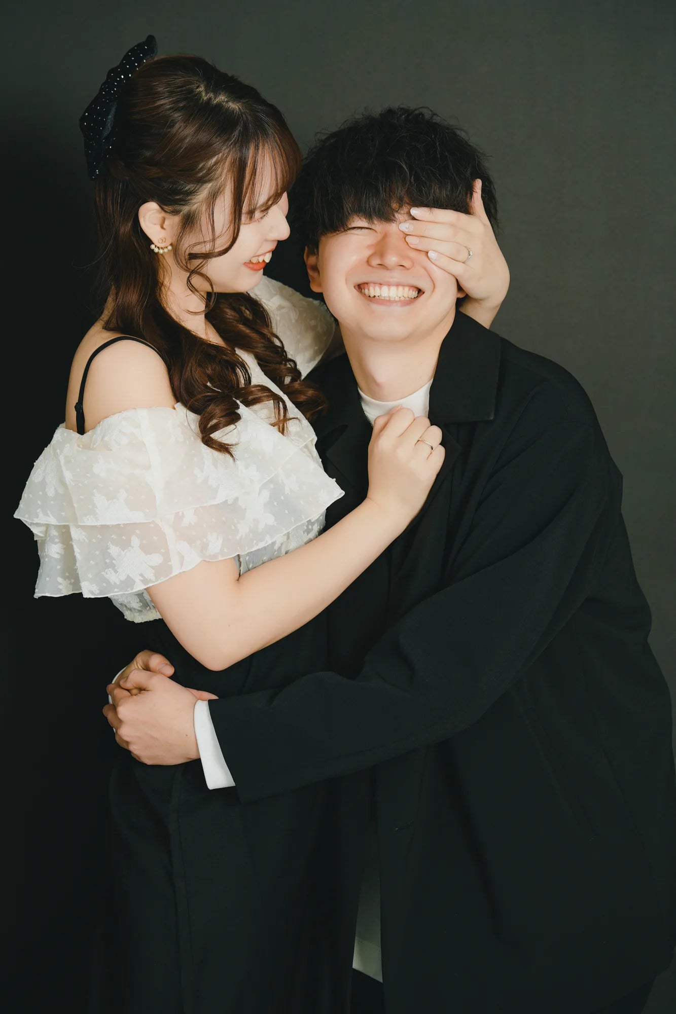 黒を基調とした衣装で笑い合うカップルの自然なスタジオフォト