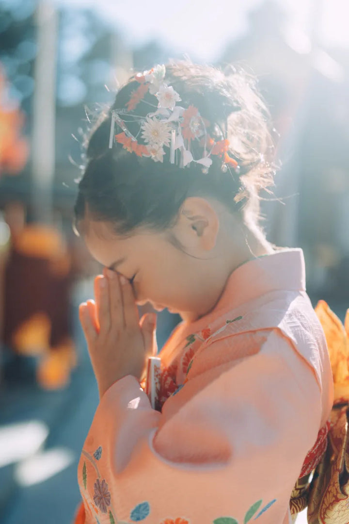 神社で手を合わせるピンクの着物姿の女の子