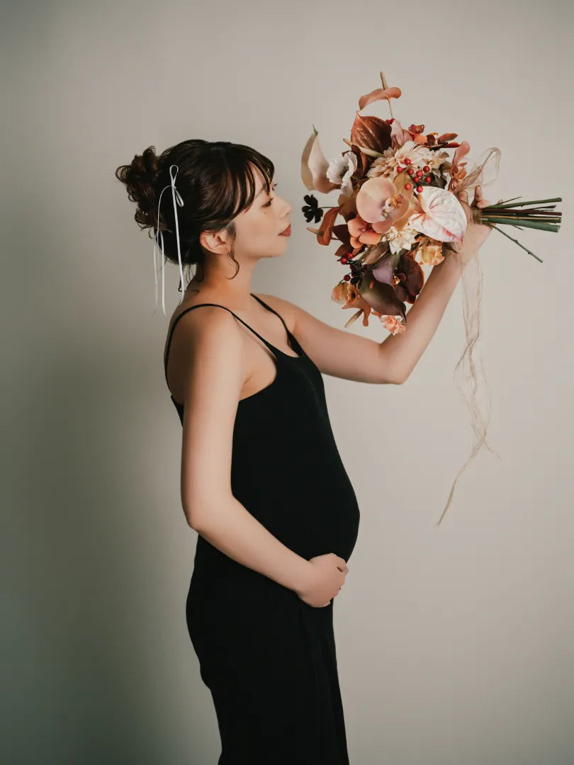 黒いドレスで花束を持つ妊婦の美しいマタニティポートレート。仙台フォトスタジオQnNe(キュンネ)