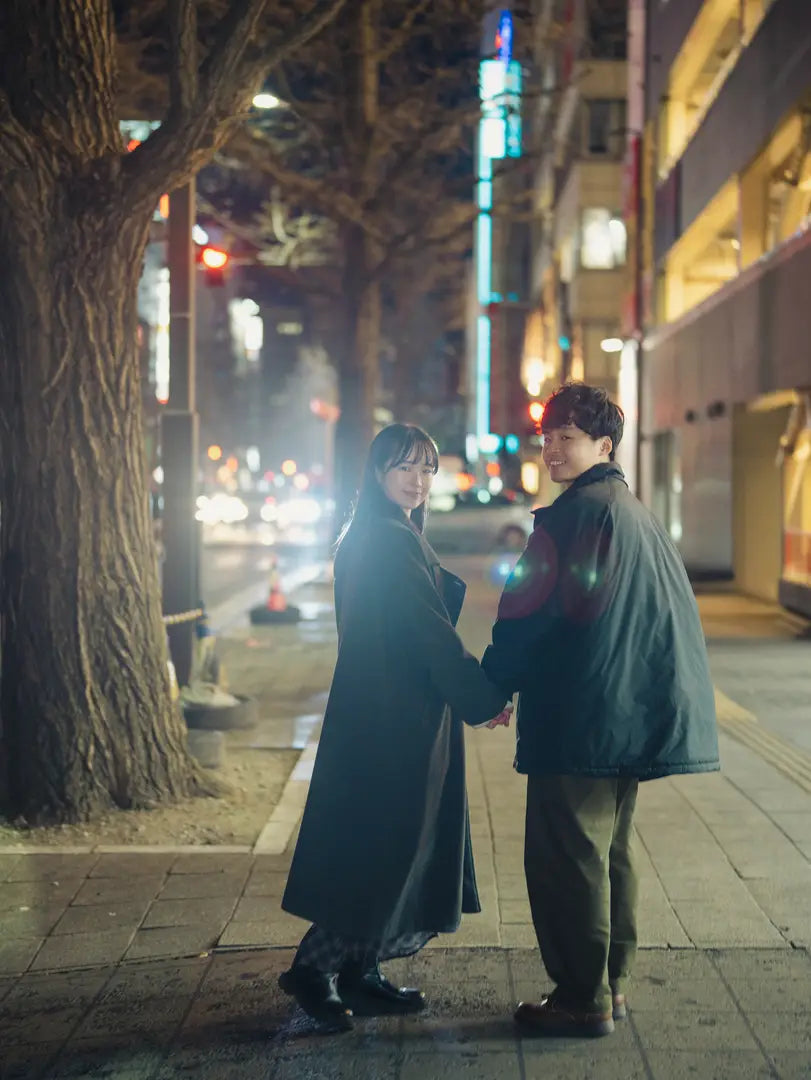 夜の街で手をつなぎ見つめ合うカップルのロケーションフォト。仙台フォトスタジオQnNe(キュンネ)