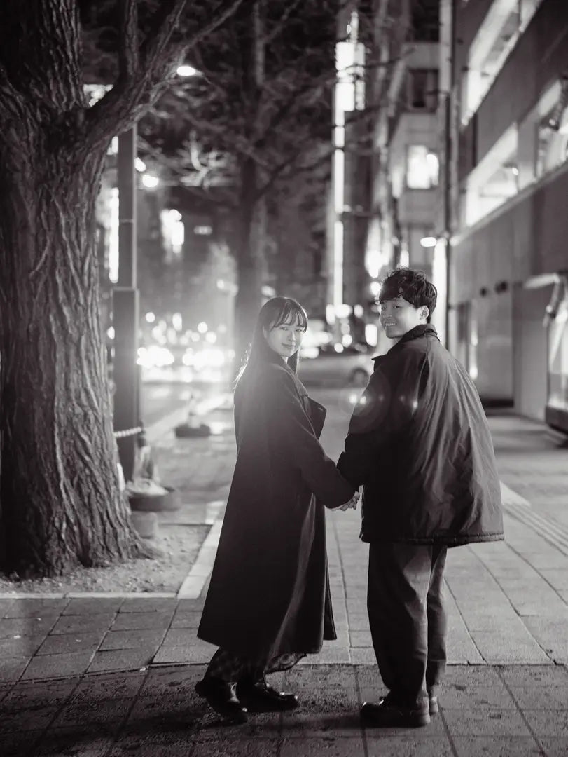 夜の街で手を取り合い振り向くカップルのモノクロ写真。仙台フォトスタジオQnNe(キュンネ)