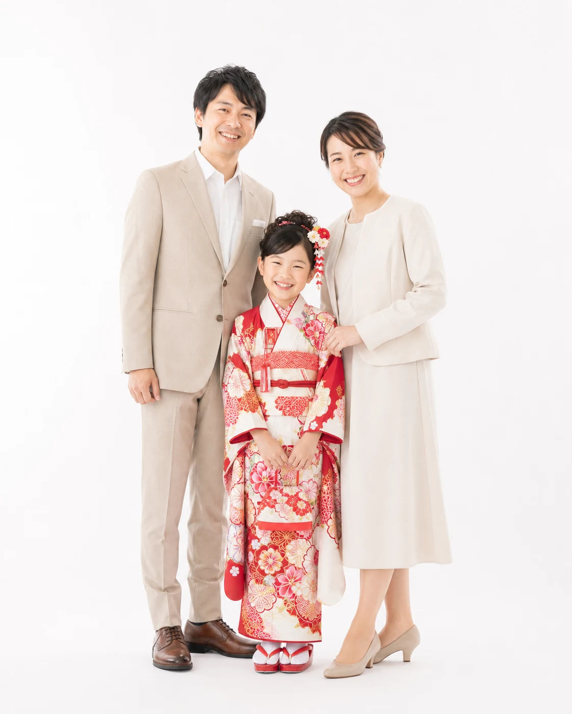 白い背景のスタジオで赤と白の着物を着た七歳の女の子と両親が並ぶ七五三家族写真