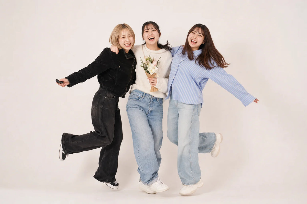 花束を持って肩を組みはしゃぐ友達3人のセルフフォト（イメージ）｜仙台フォトスタジオQnNe（キュンネ）