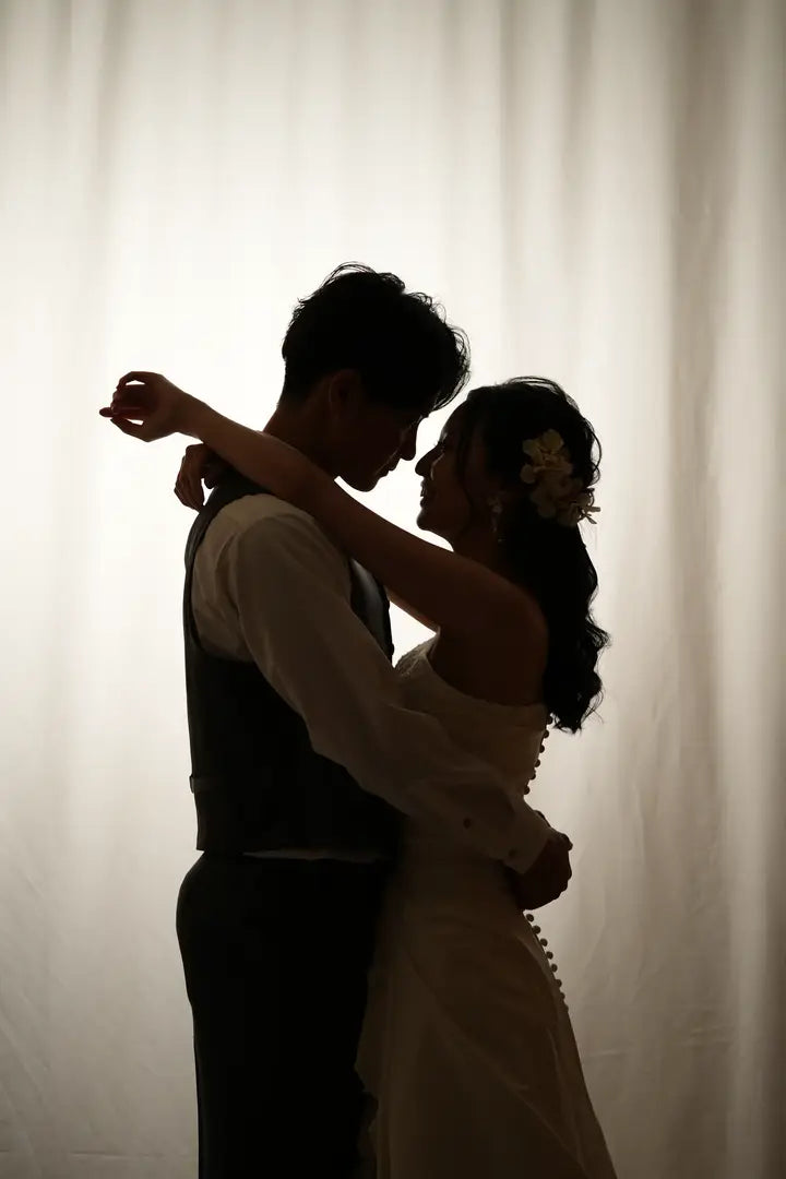 カーテン越しに抱き合う新郎新婦のロマンチックなシルエット写真。仙台フォトスタジオQnNe(キュンネ)