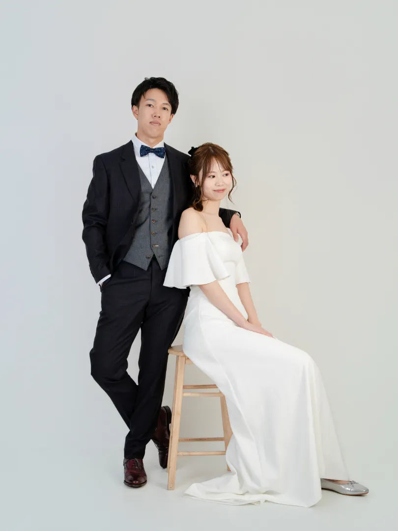 白いドレスとタキシード姿の新郎新婦がスタジオで微笑むウェディングフォト。仙台フォトスタジオQnNe(キュンネ)